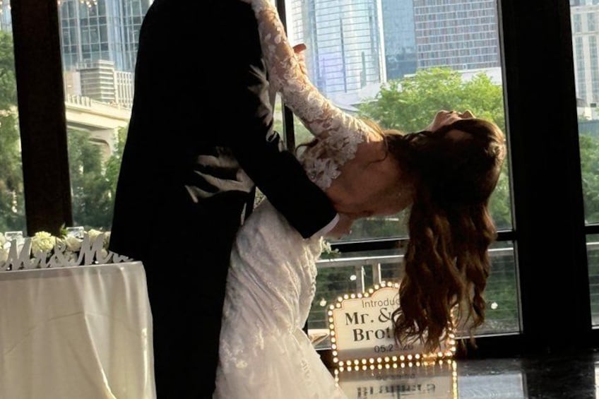 A couple in wedding attire, a man in a black suit and a woman in a white dress, standing in front of a sign that reads 'Mr. & Mrs. Brown.' 3