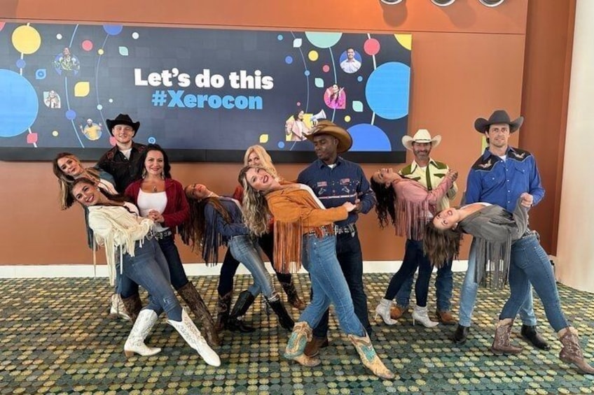 A group of people in cowboy attire posing in front of a wall with the text 'Let's do this #Xerocon'. 1