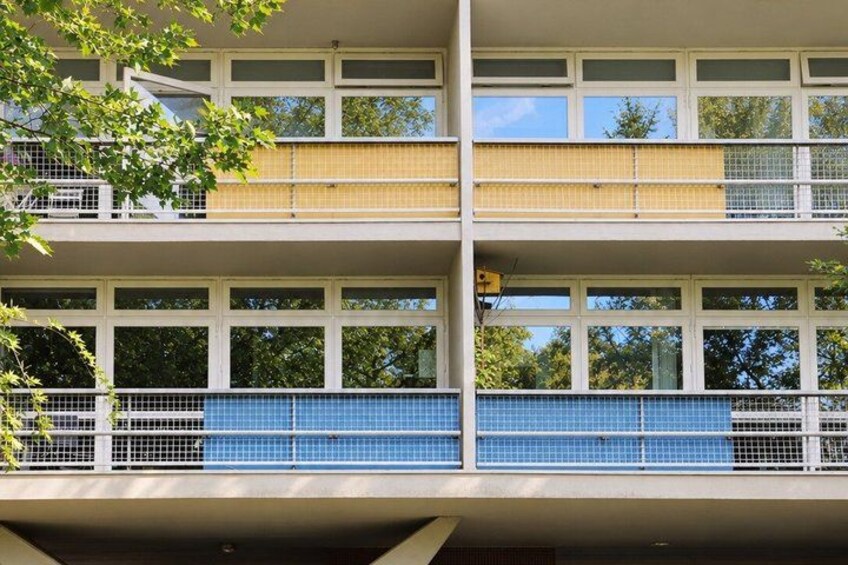 A modern building with multiple balconies, large windows, and a blue-tiled ground floor. 5
