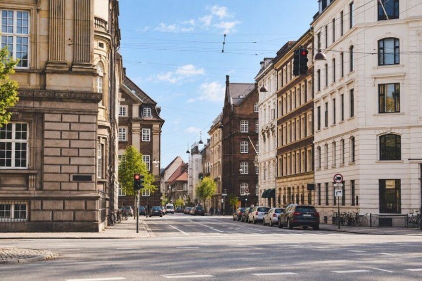 A street with parked cars, buildings, and a traffic light. 5