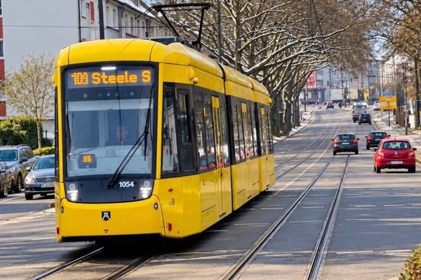 A yellow tram with the number 1054 on a tram track, surrounded by cars and buildings. 4