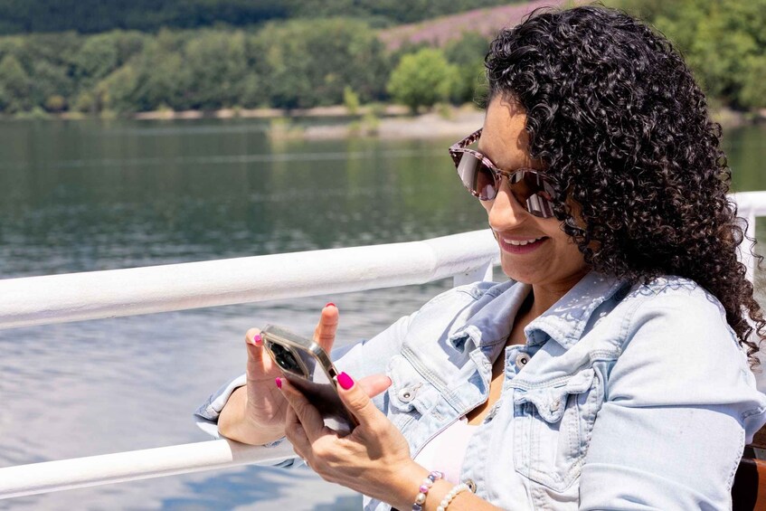 A person with curly hair, wearing a denim shirt, holding a smartphone, and looking at it. 2