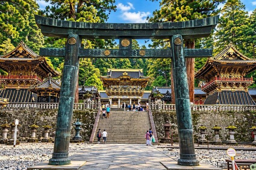 A traditional Japanese torii gate leading to a temple complex with multiple buildings. 3