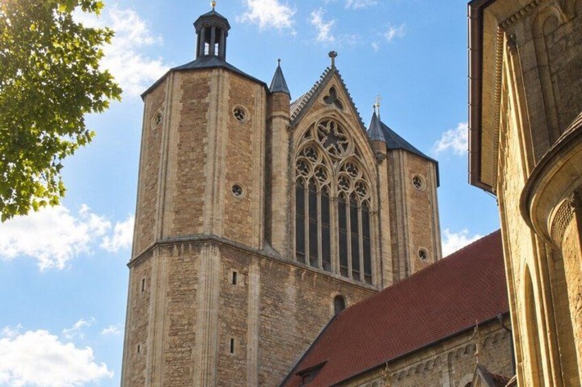 A tall church tower with a pointed roof and a large rose window. 2