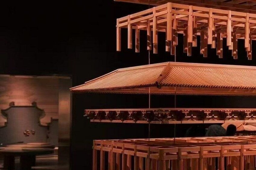 A multi-tiered wooden structure with a traditional roof design, possibly a pavilion or a part of a larger architectural installation. 2