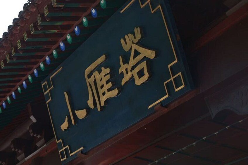A traditional Chinese architectural structure with ornate details and a sign with Chinese characters. 5