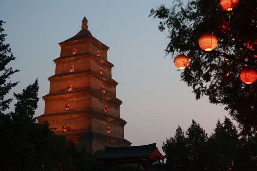 A multi-tiered pagoda with illuminated windows, surrounded by trees and traditional architecture. 3