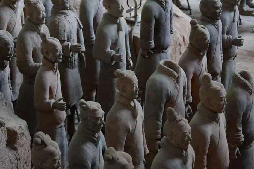Terracotta soldiers in a row, some holding tools, standing in a formation. 1