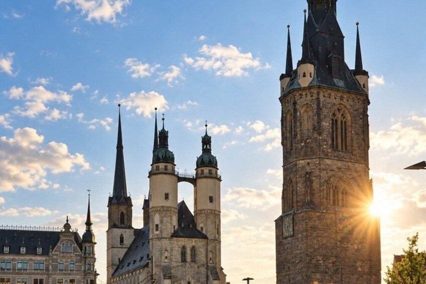 A historic church with multiple spires and a prominent tower, set against a clear sky with the sun shining. 3