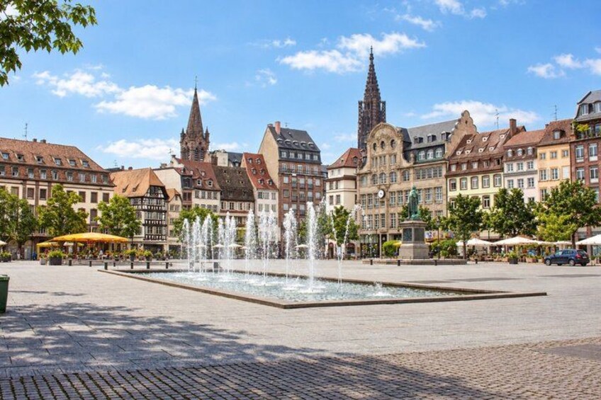 A square with a fountain, historic buildings, and a church spire. 4