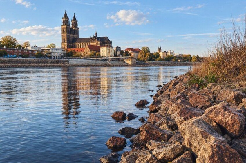 A river with a rocky shore, a bridge, and a historic building with towers. 2