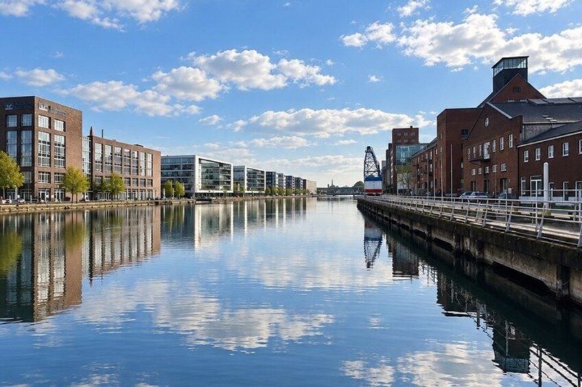 A calm river reflecting buildings, a bridge, and a clear sky. 3