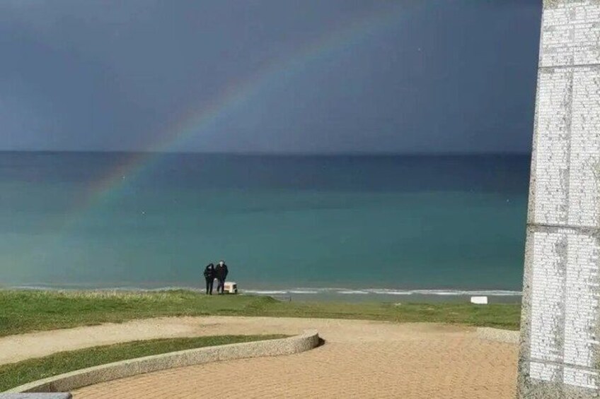 A beach with a rainbow, a sandy area, and a structure in the foreground. 4