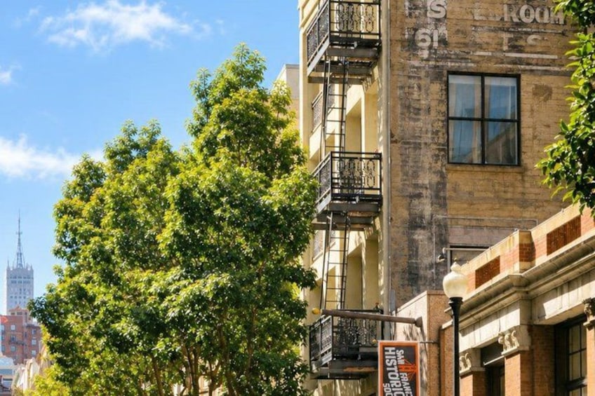 A building with a fire escape, trees, and a sign. 3