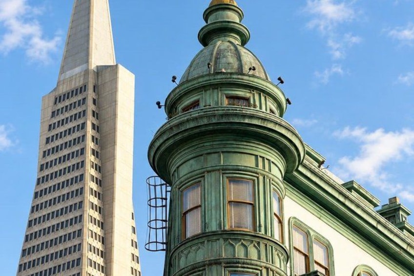 A historic building with a green dome and a tall skyscraper in the background. 1