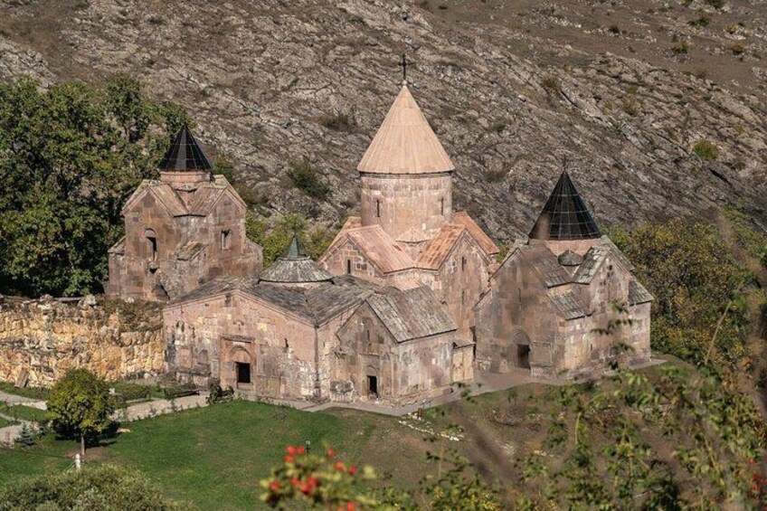 A historic church with a central dome and two bell towers, surrounded by a grassy area and rocky terrain. 5