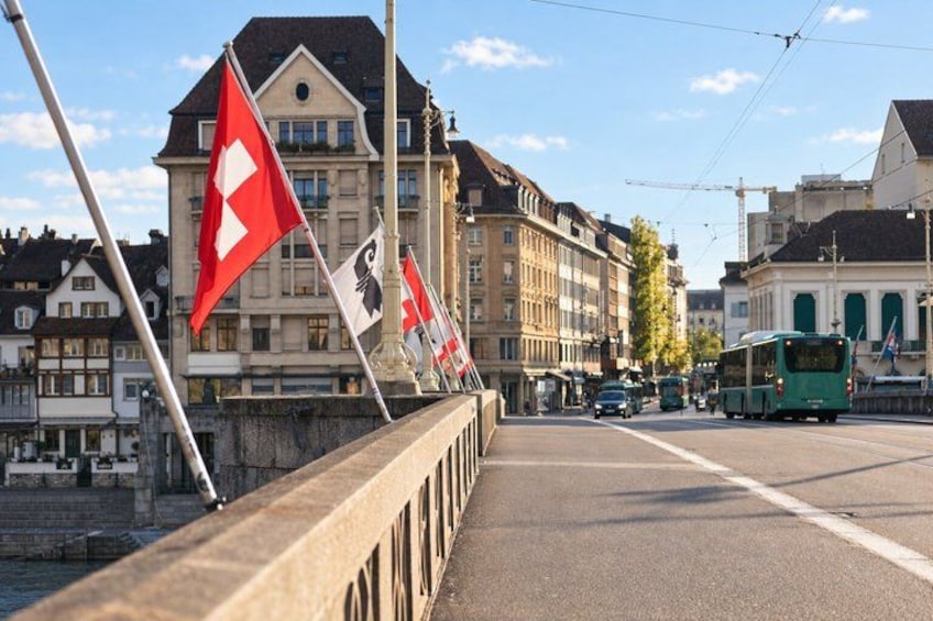 A bridge with flags, a tram, and buildings in the background. 3