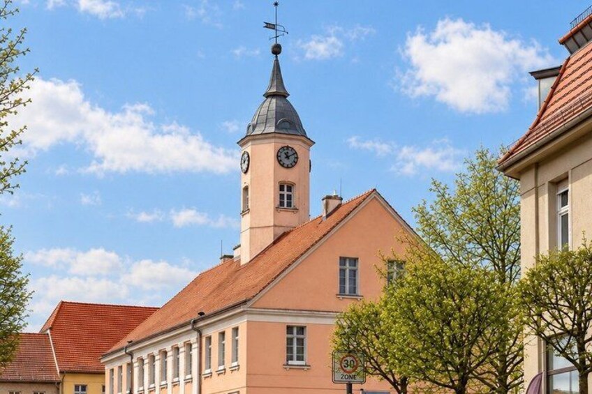 A building with a clock tower, a red-roofed building, and a 30 km/h speed limit sign. 2