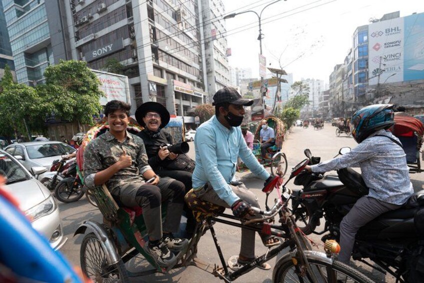 A busy street with motorcycles and cars, buildings with signs, and a clear sky. 3