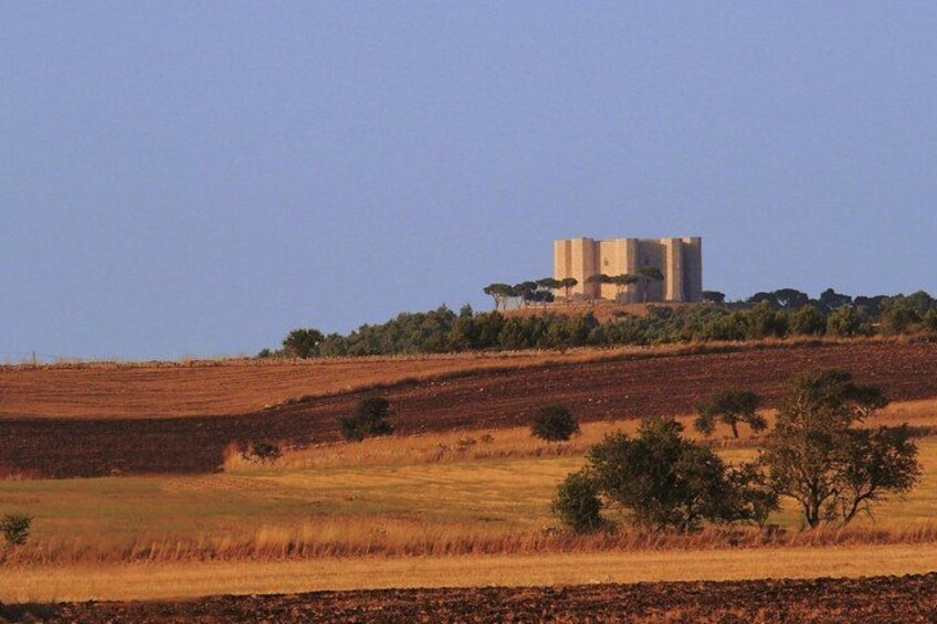 A landscape with rolling hills, a clear sky, and a structure resembling a tower or building on a hill. 2