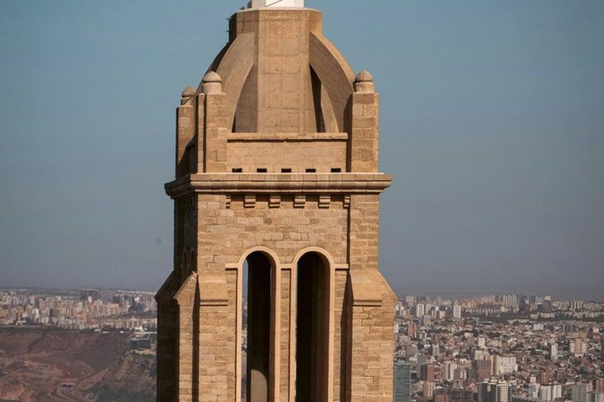 Une haute tour de pierre, dotée de fenêtres en arc de cercle et surmontée d’un dôme, qui domine un paysage urbain dense et bâti. 3