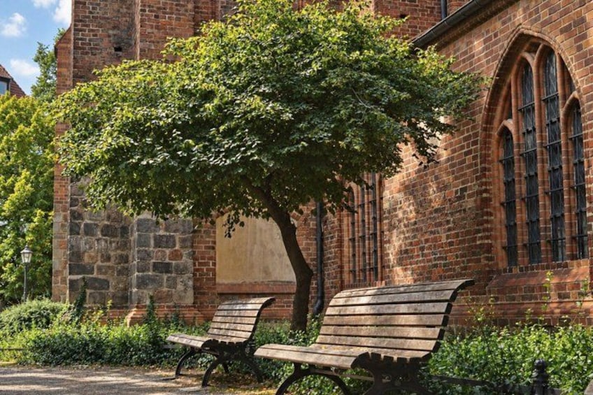 A brick building with arched windows and a tree in front. 4