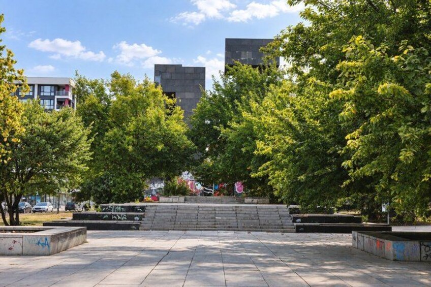 A public square with benches, trees, and buildings in the background. 5