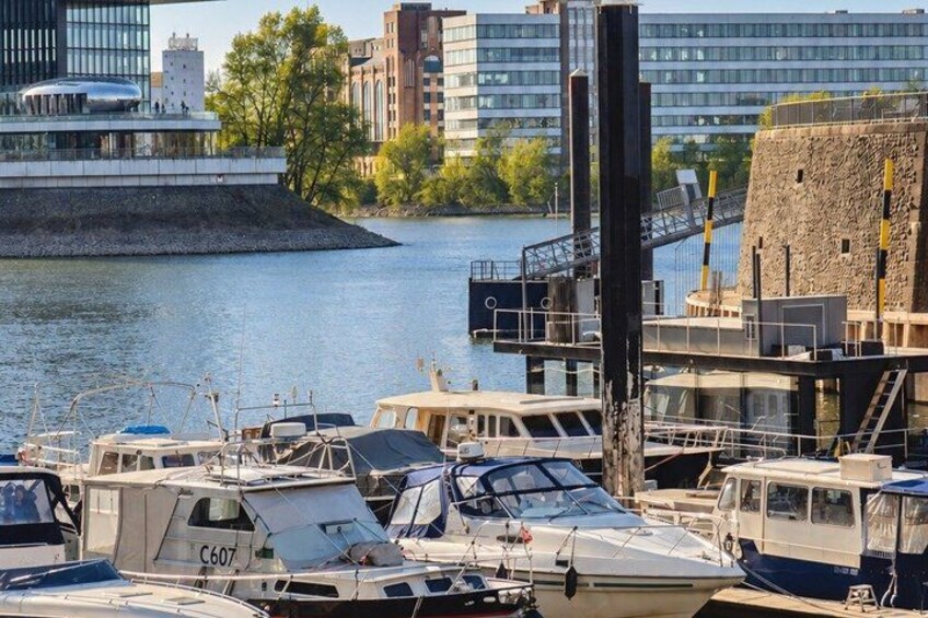 A marina with boats docked, a river, and buildings in the background. 3
