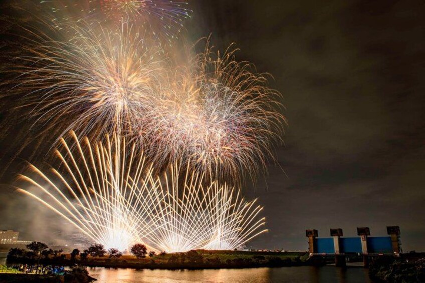 Fireworks over a body of water with a bridge in the background. 3