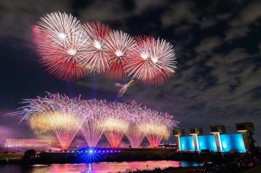 Fireworks over a city skyline with illuminated buildings. 1