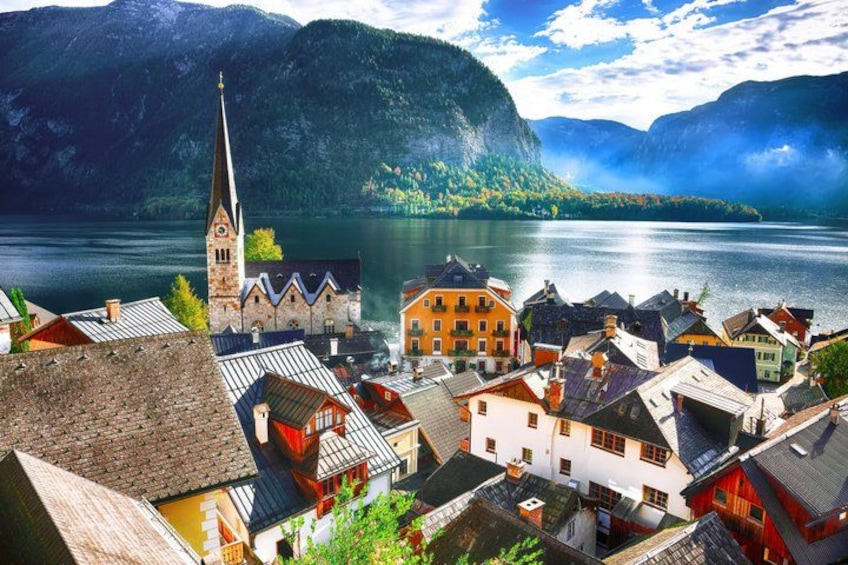 A town with a church, buildings, and a lake surrounded by mountains. 3