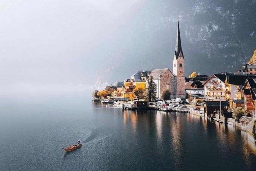 A calm lake with a boat, a church, and colorful buildings along the shore. 4