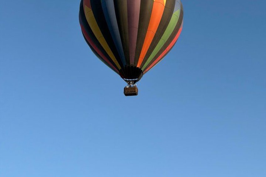 A hot air balloon with multicolored stripes against a clear blue sky. 4