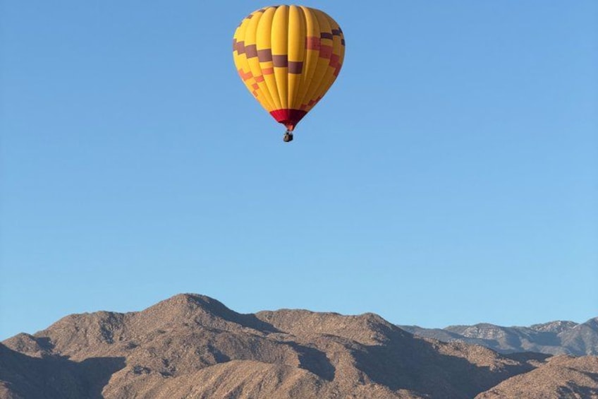 A hot air balloon flying over a mountainous landscape. 1