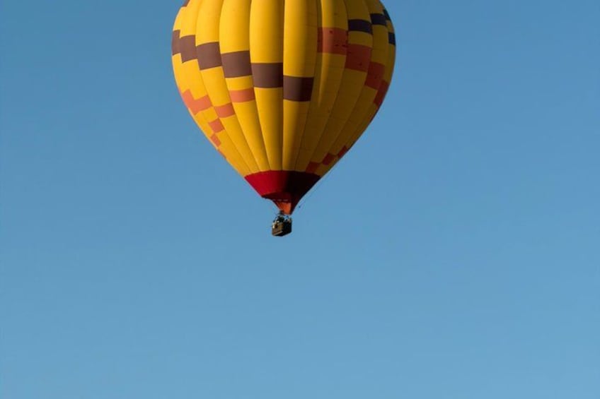 A hot air balloon with a yellow and red pattern, flying against a clear blue sky. 2