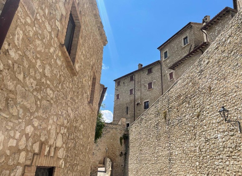 A narrow street with stone buildings, a clear sky, and a street lamp. 3