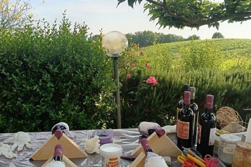 A picnic setup with wine bottles, a lamp post, and a table in a lush garden. 2