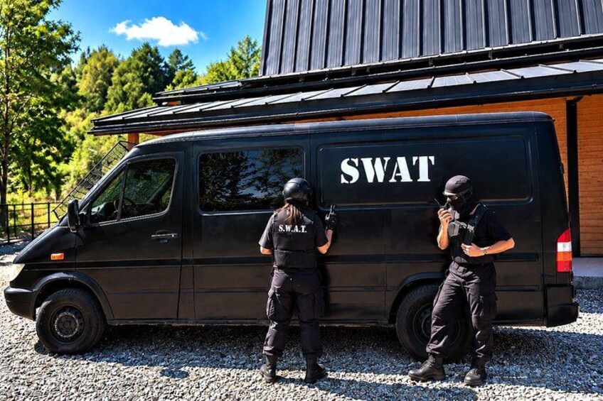 Two SWAT officers standing beside a SWAT van. 4
