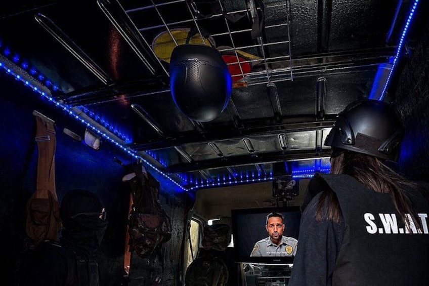 A room with blue LED lights, a basketball hoop, and a person wearing a helmet with 'S.W.A.T' on the back. 1