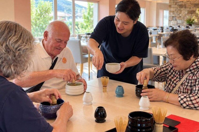 A group of people sitting around a table with bowls and chopsticks, engaged in a meal. 3