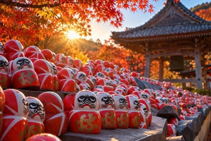 A collection of red and white Japanese dolls with gold designs, arranged in rows on a stone pathway. 1