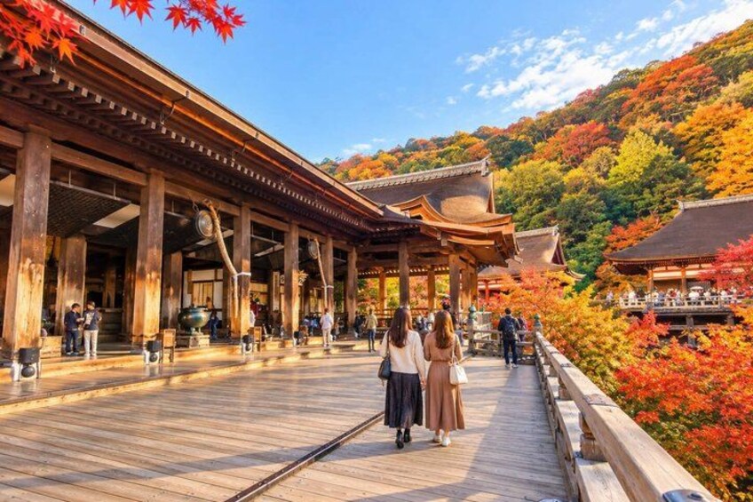 A traditional Japanese building with a wooden deck, surrounded by autumn foliage. 4
