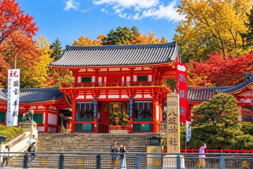 A traditional Japanese building with red and white colors, surrounded by autumn trees. 5