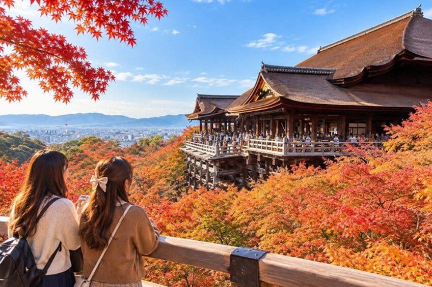 A traditional Japanese building with a wooden structure and a viewing platform, surrounded by autumn foliage. 2