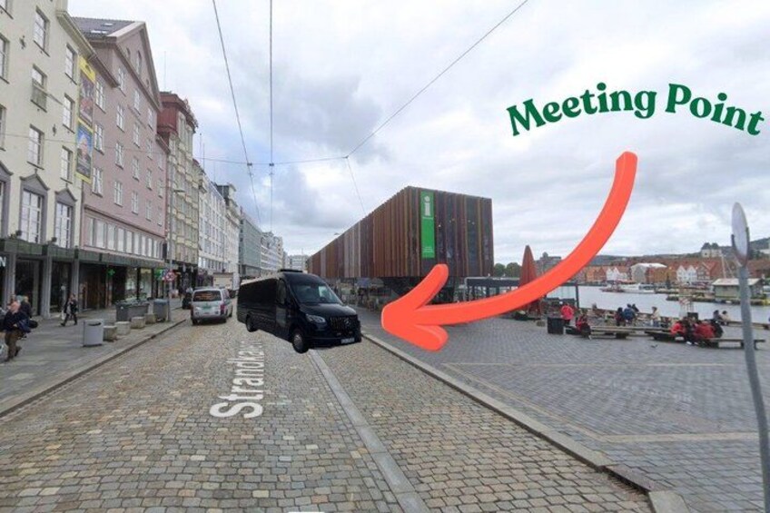 A cobblestone street with a tram, buildings, and a body of water. 2