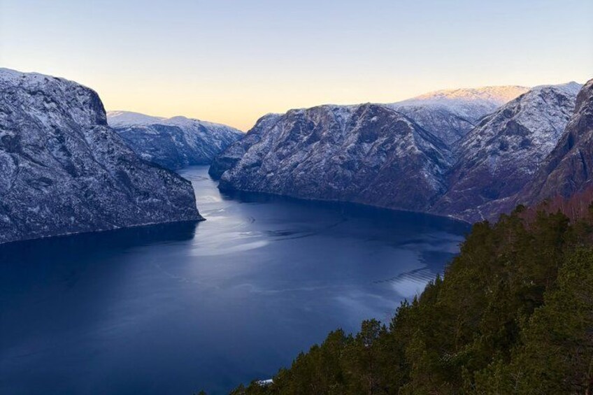 A snow-covered mountain landscape with a calm lake and dense forest. 1