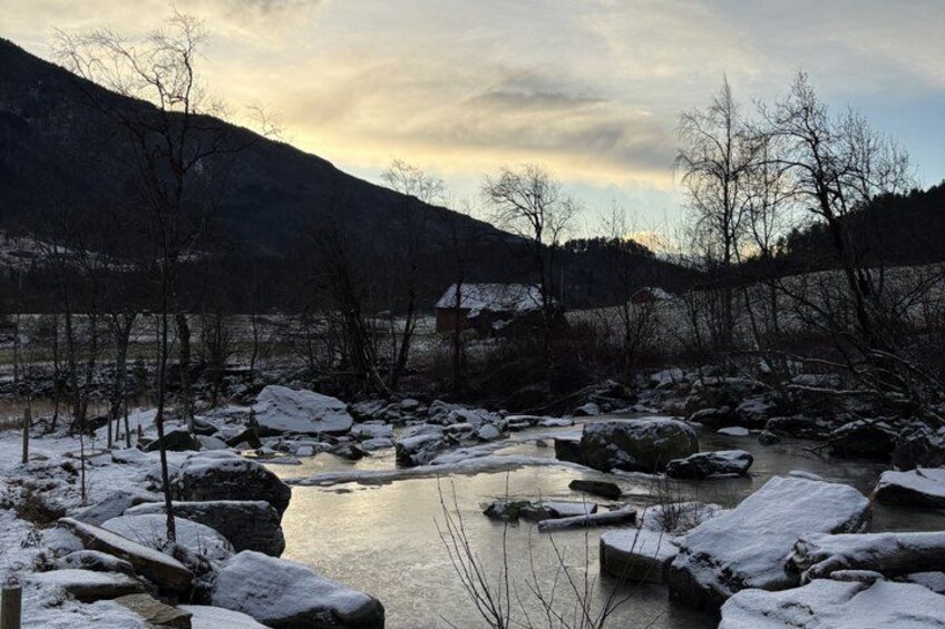 A frozen river with snow-covered rocks and trees in a mountainous landscape. 5