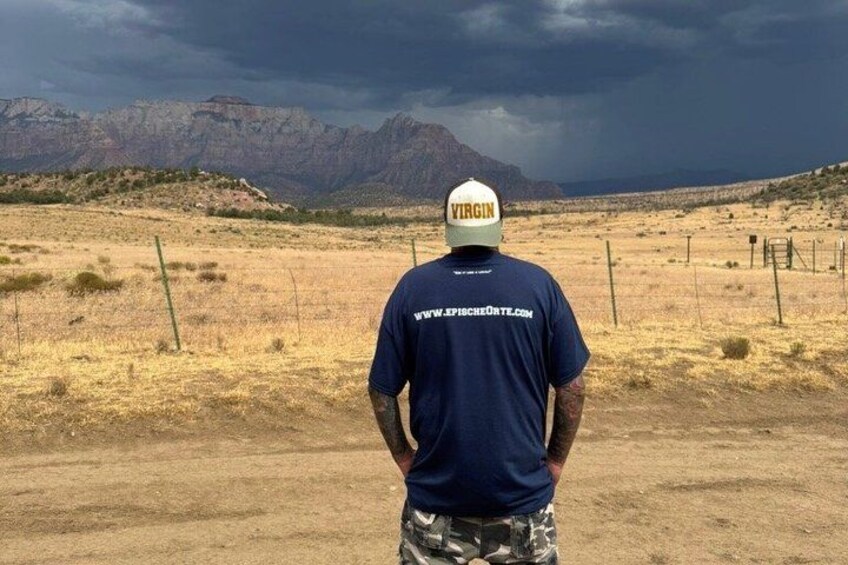 A person standing in a desert landscape with mountains in the background. 2