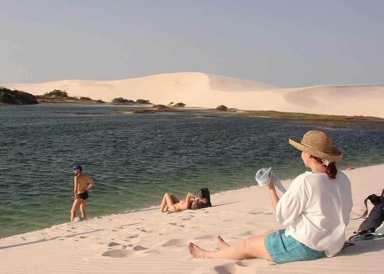 Ein Strand mit Menschen, die sich sonnen und im Wasser schwimmen. 1