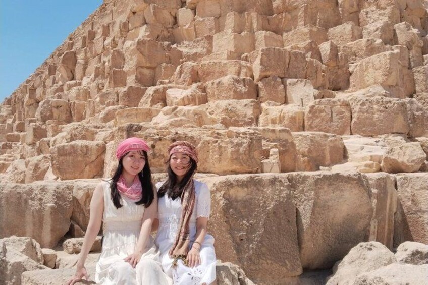 Two individuals sitting in front of a large stone pyramid. 2